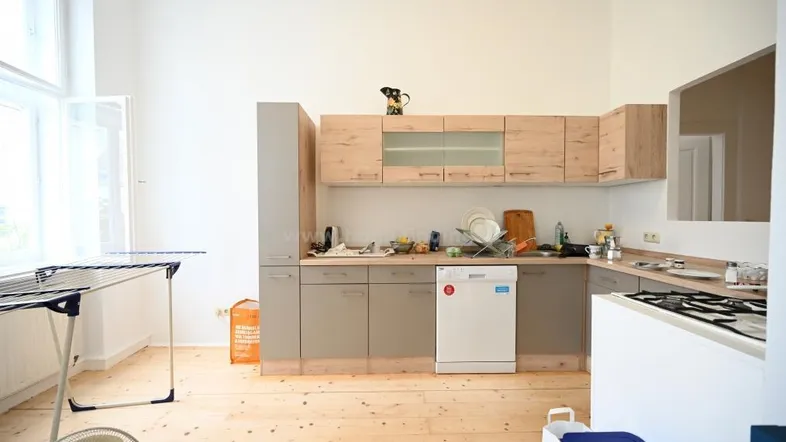 Helle Küche mit Holzfußboden, modernen Schränken und einem Fenster, das viel Tageslicht hereinlässt.