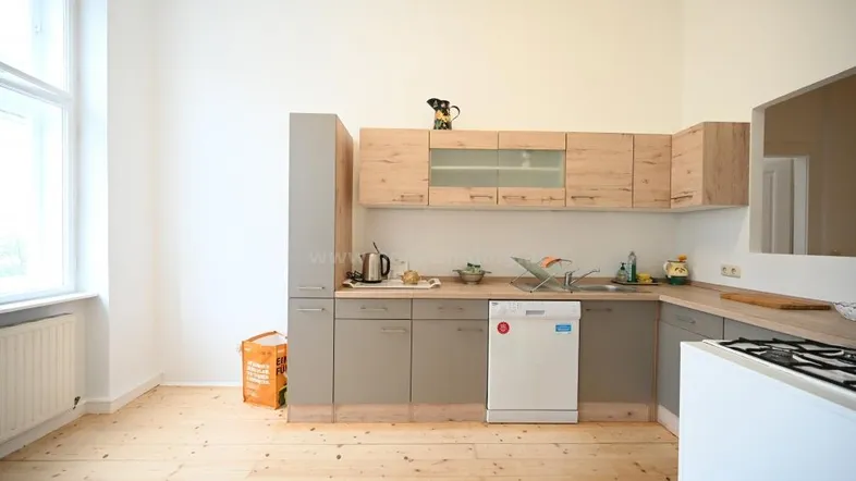 Helle Küche mit Holz- und Grautönen, ausgestattet mit Geschirrspüler und Fenster für natürliches Licht.