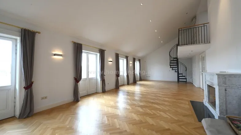 Großzügiges Wohnzimmer mit Fischgrätparkett, Kamin und eleganter Wendeltreppe zu einer Galerie.
