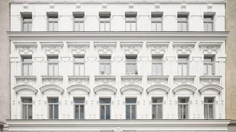 Weißes, klassisches Gebäude mit reich verzierten Fassadendetails und modernen Dachgauben in der Stadt.