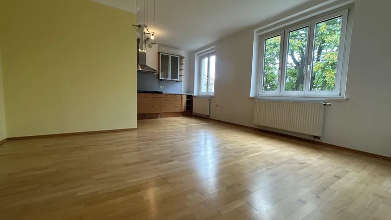 Heller offener Wohn- und Essbereich mit Holzboden, gelber Wand und integrierter Küchenzeile.