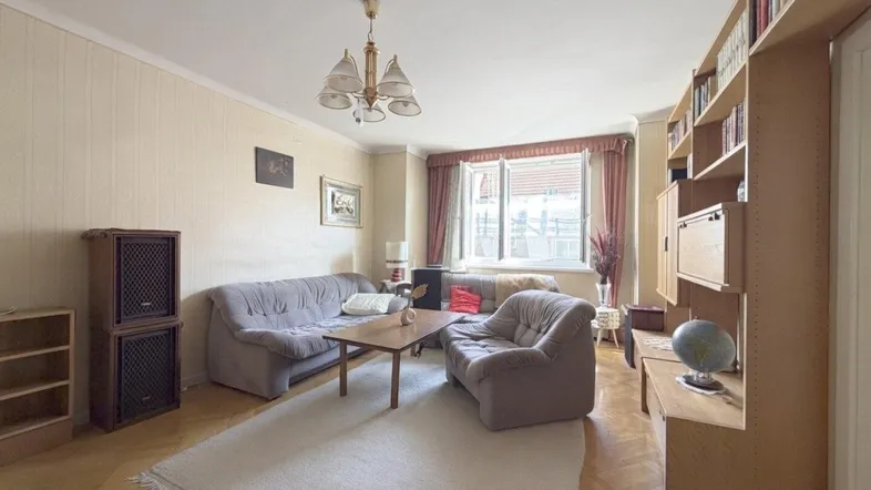 Gemütliches Wohnzimmer mit Fischgrätparkett, großem Sofa und Bücherregal, das viel Stauraum bietet.