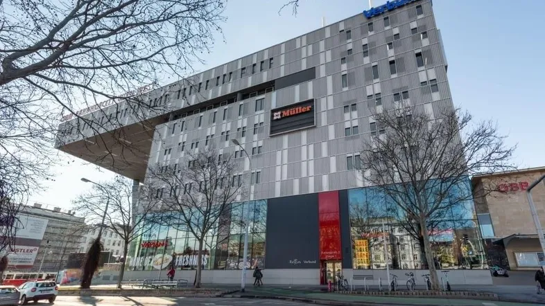 Modernes Geschäftsgebäude mit markanter Architektur und großen Glasflächen an einem sonnigen Tag.