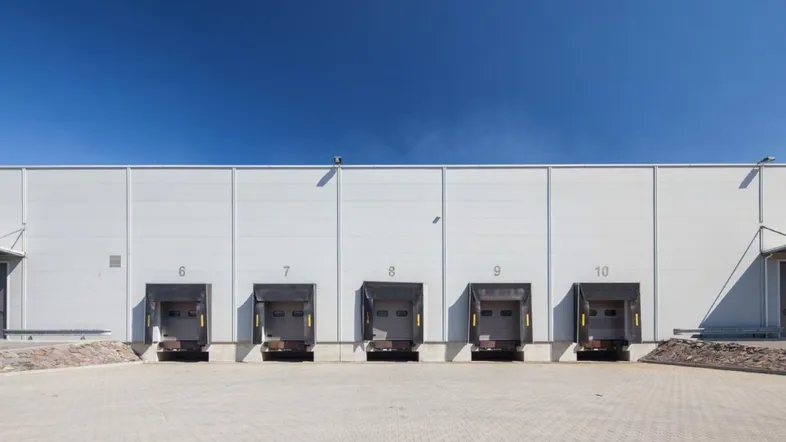 Moderne Lagerhalle mit mehreren Laderampen unter klarem blauem Himmel, bereit für den Betrieb.