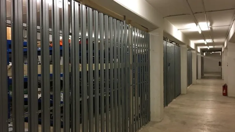 Geräumiger Kellerraum mit individuellen Lagerabteilen und funktionaler Beleuchtung.
