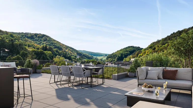 Geräumige Terrasse mit Essbereich und Lounge-Möbeln, umgeben von grünen Hügeln und Weitblick.