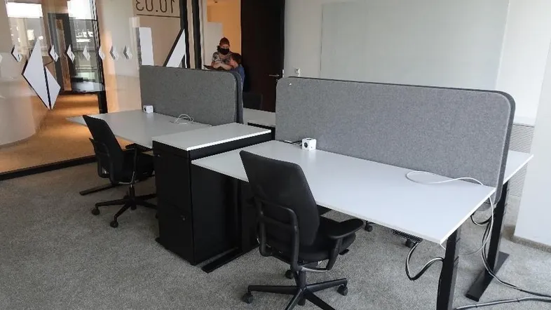 Moderne Büroräume mit ergonomischen Schreibtischen und Teppichboden, ideal für konzentriertes Arbeiten.