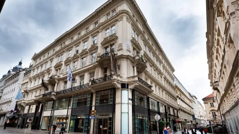 Historisches Gebäude mit klassischer Architektur und Geschäften im Erdgeschoss an einer belebten Straße.