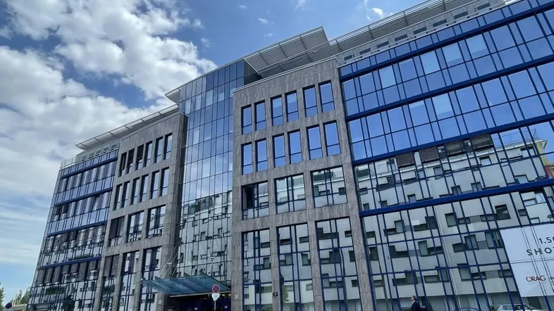 Modernes Bürogebäude mit markanter Glasfassade und klaren Linien in urbaner Umgebung, gut gepflegt.