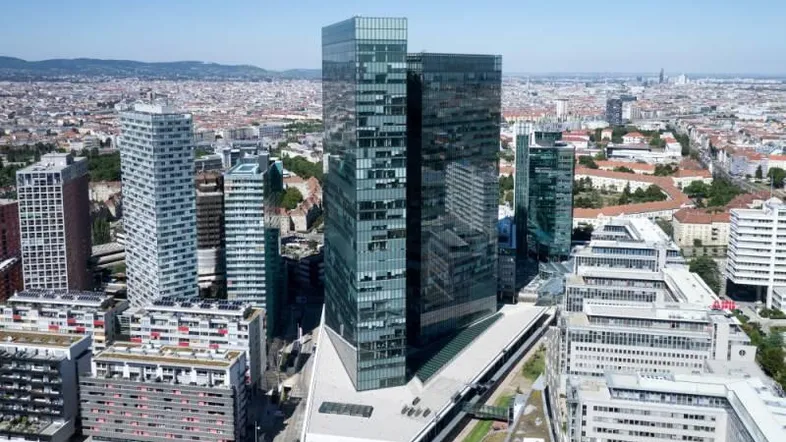 Luftaufnahme eines modernen Bürokomplexes mit Glasfassaden in einer städtischen Umgebung und umliegenden Gebäuden.