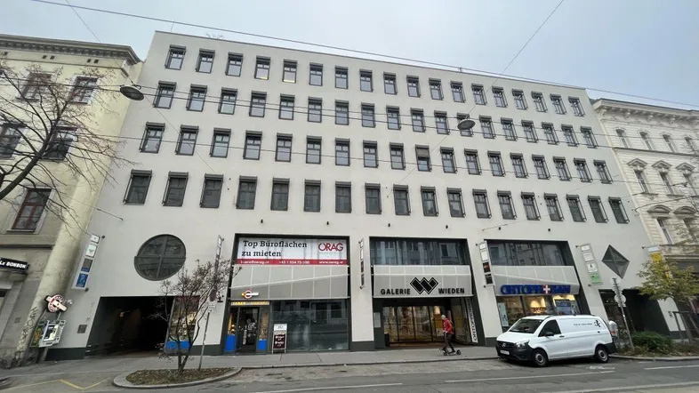 Modernes Geschäftsgebäude mit mehreren Etagen, Ladenflächen im Erdgeschoss und Büros darüber.
