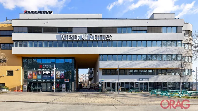 Modernes Geschäftsgebäude mit markanter Glasfassade, vielen Fenstern und Außenrollläden in einem gepflegten Zustand.