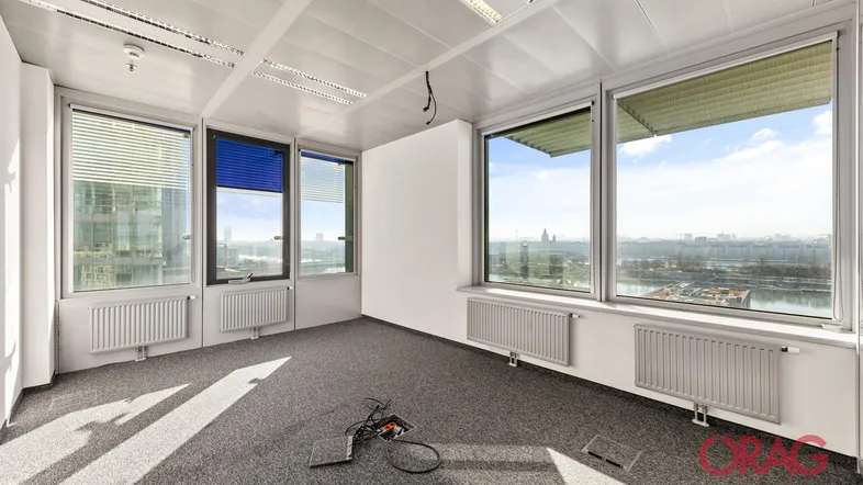 Geräumiges, leeres Büro mit großen Fenstern, die einen weiten Blick auf die Stadt und den Fluss bieten.