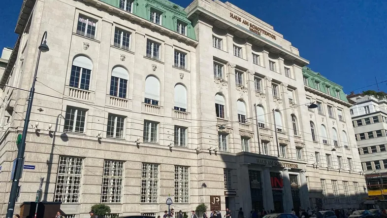 Historisches Gebäude 'Haus am Schottentor' mit klassischer Steinfassade und grünen Kupferdächern in der Stadt.