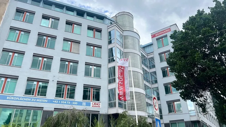 Modernes Bürogebäude mit vielen Fenstern und einer Glasfassade in städtischer Umgebung.