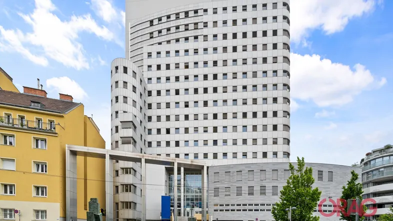 Modernes Hochhaus mit vielen Fenstern und einer geschwungenen Fassade unter blauem Himmel.