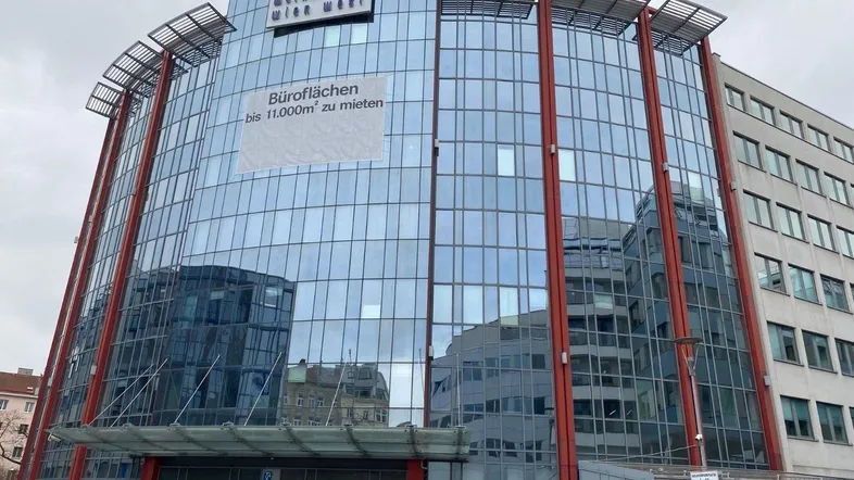 Moderne Bürogebäude-Fassade mit großer Glasfront und einem Banner für Mietflächen in der Stadt.