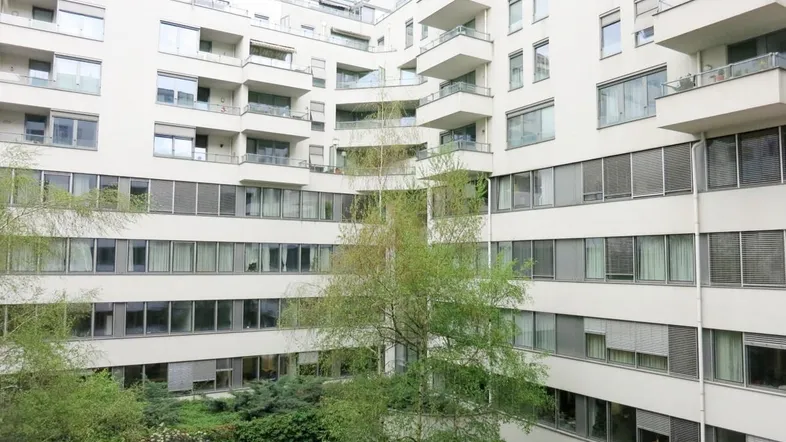 Moderne Wohnanlage mit zahlreichen Balkonen und einem begrünten Innenhof, der eine ruhige Atmosphäre schafft.