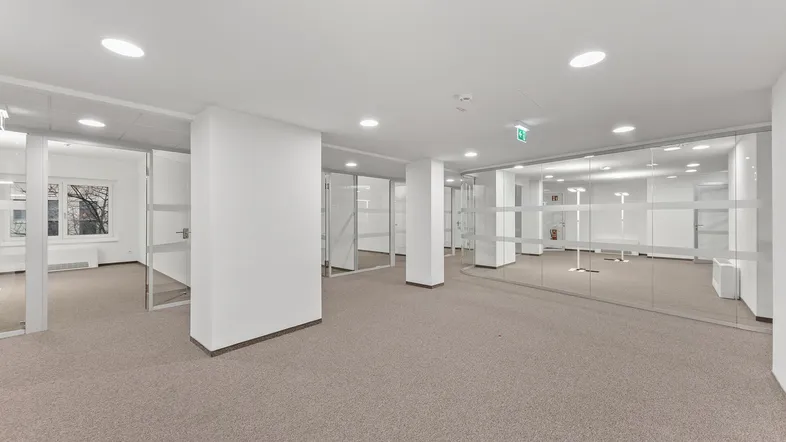 Helles, modernes Büro mit Teppichboden und Glaswänden, ideal für flexible Arbeitsbereiche und viel Tageslicht.
