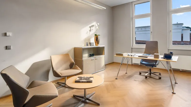Modernes Büro mit Fischgrätparkett, großen Fenstern und stilvollen Möbeln, ideal für konzentriertes Arbeiten.