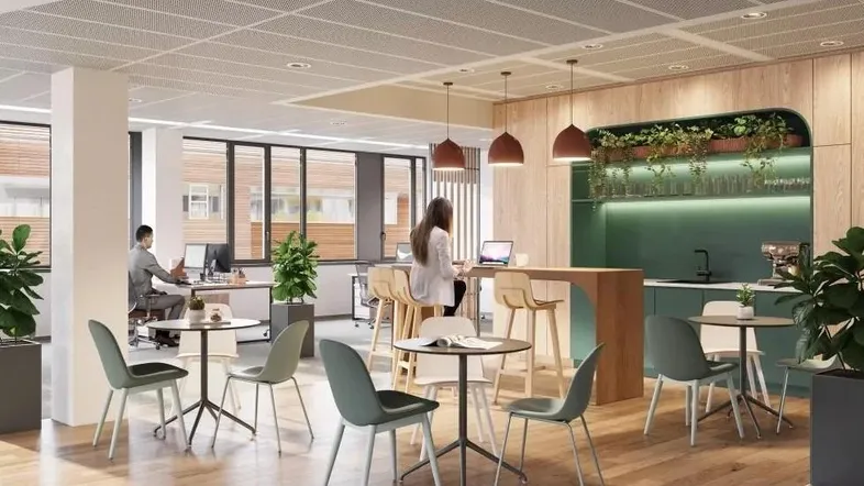 Moderner offener Bürobereich mit Holzboden, Arbeitsplätzen und einer Teeküche mit Sitzgelegenheiten.