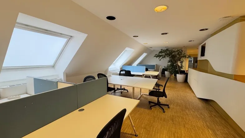 Modernes Großraumbüro mit Dachfenstern, hellen Arbeitsplätzen und Holzboden, ideal für kreative Teams.