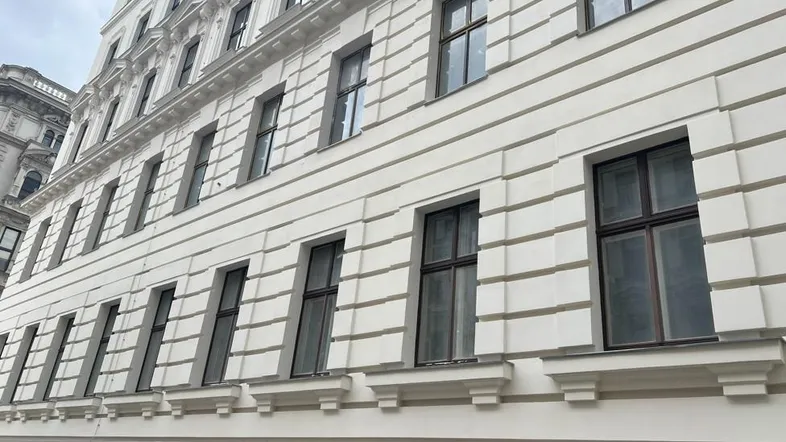 Eindrucksvolle weiße Fassade eines klassischen Gebäudes mit vielen Fenstern und architektonischen Details.