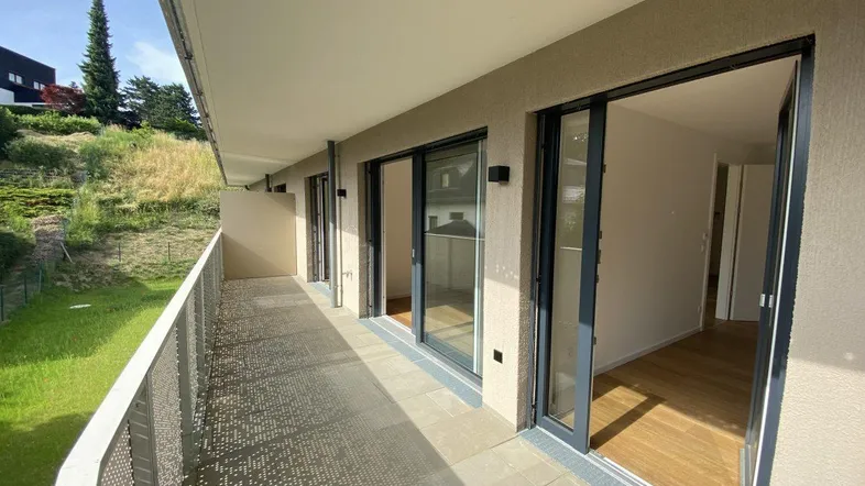 Geräumiger Balkon mit moderner Lochblechbrüstung und Blick ins Grüne.