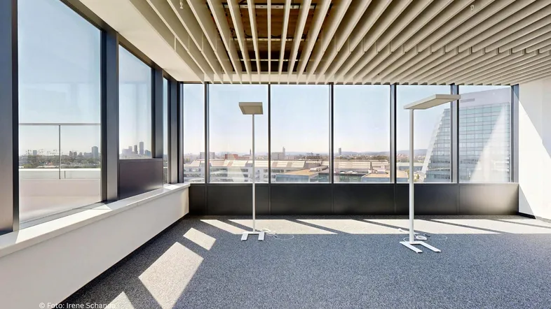 Geräumiges Büro mit großen Fenstern, Teppichboden und modernem Deckendesign, bietet weite Stadtblicke.