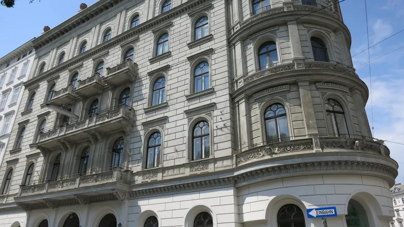 Historisches Eckgebäude mit reich verzierten Fassaden, vielen Fenstern und klassischer Architektur.