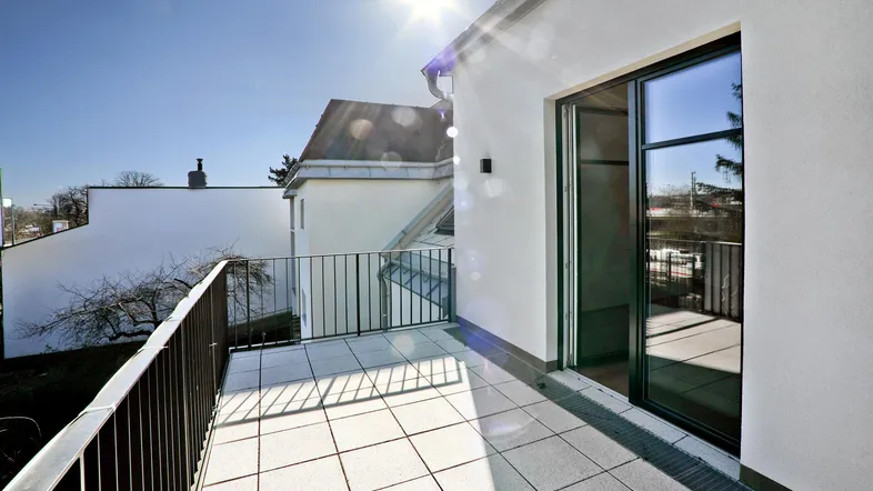 Sonniger Balkon mit Fliesenboden und Blick auf die Umgebung, ideal für Entspannung im Freien.