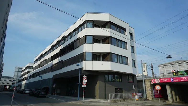 Modernes Bürogebäude mit markanter Architektur und großen Fenstern an einer städtischen Straße.