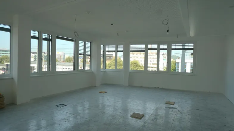 Heller, leerer Büroraum mit vielen Fenstern und Blick auf die Stadt, bereit für den Ausbau.