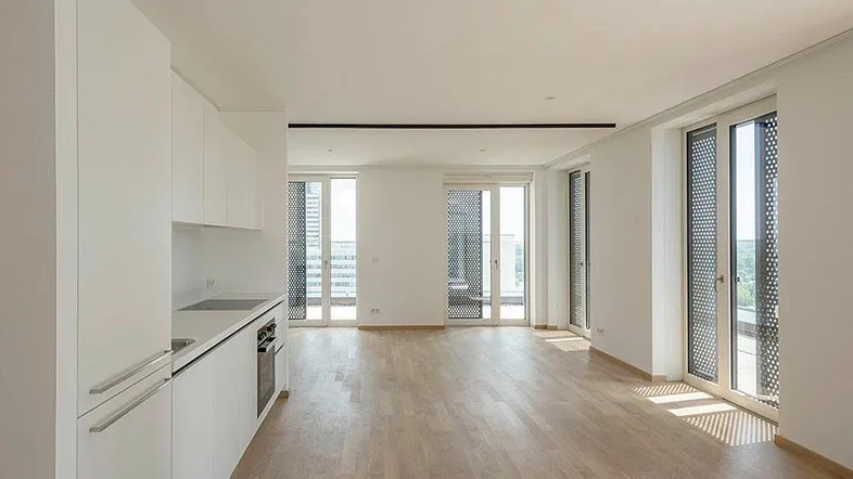 Helle, offene Wohnküche mit modernen weißen Schränken und Parkettboden, mit Zugang zu einem Balkon.