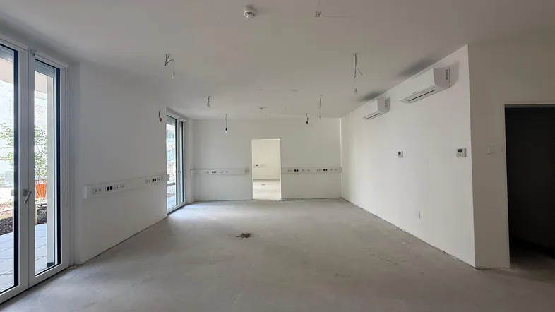 Geräumiger, unmöblierter Gewerberaum mit großen Fenstern und Klimaanlagen, bereit für den Ausbau.