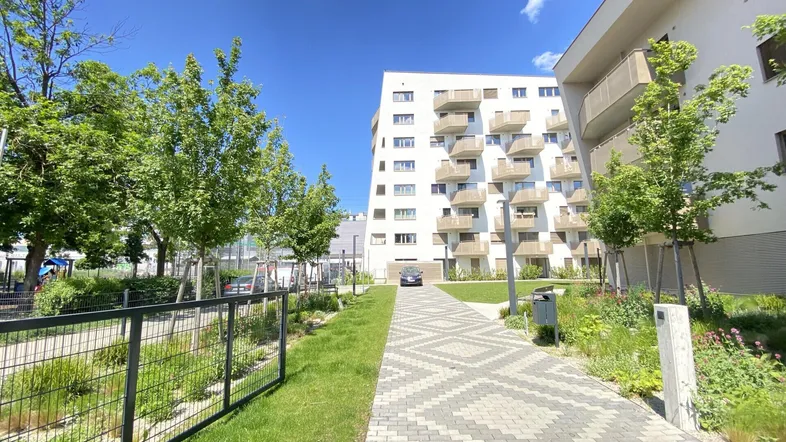 Moderne Wohngebäude mit Balkonen und gepflegten Grünflächen unter blauem Himmel.