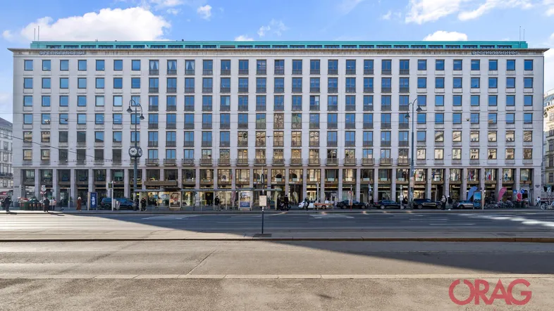 Großes Bürogebäude mit vielen Fenstern und Geschäften im Erdgeschoss, an einer belebten Straße gelegen.