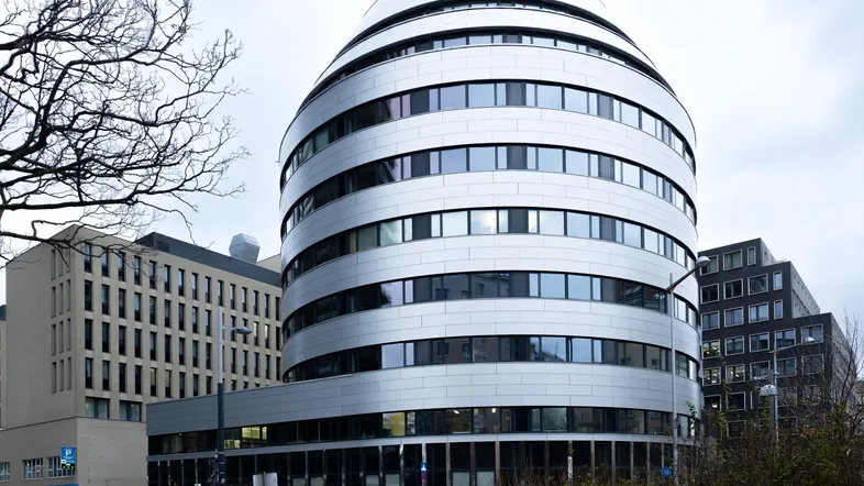 Modernes, geschwungenes Bürogebäude mit vielen Fenstern und einer markanten Fassade.