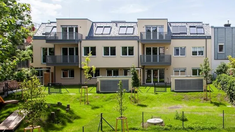 Moderne Wohnanlage mit gepflegtem Gemeinschaftsgarten und Spielplatz für Kinder.
