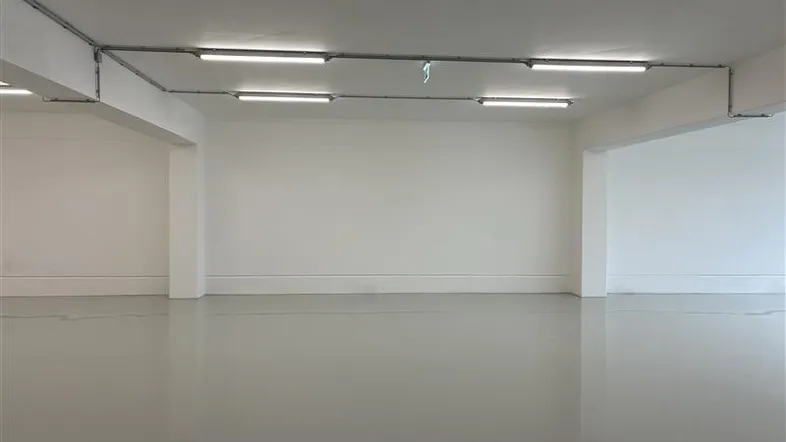 Großer, leerer Raum mit hellgrauem Boden und Deckenbeleuchtung, ideal für Büro oder Gewerbe.