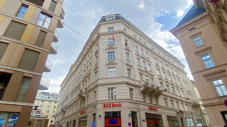 Klassisches Eckgebäude mit historischer Architektur und einer Bankfiliale im Erdgeschoss an einer belebten Straße.