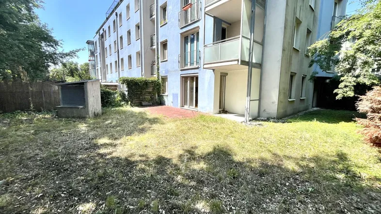 Außenansicht eines modernen Gebäudes mit Gartenbereich, Terrasse und kleinem Schuppen.