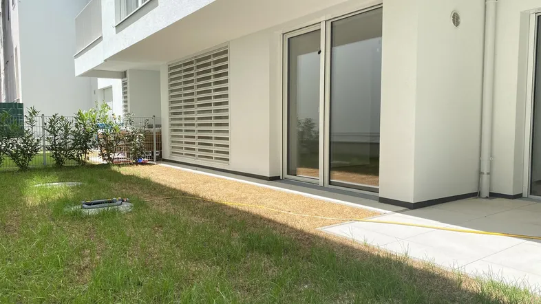 Kleiner Gartenbereich mit Rasenfläche und Zugang zu den großen Glasschiebetüren des Erdgeschosses.