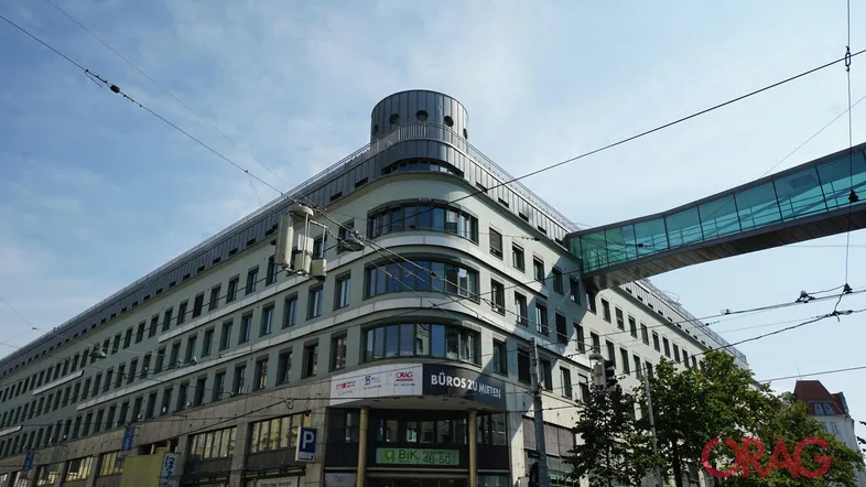 Modernes Bürogebäude mit markanter Architektur, vielen Fenstern und einer gläsernen Verbindungsbrücke.
