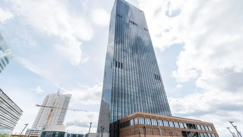 Modernes Hochhaus mit Glasfassade und Wolkenkratzer-Architektur unter bewölktem Himmel.