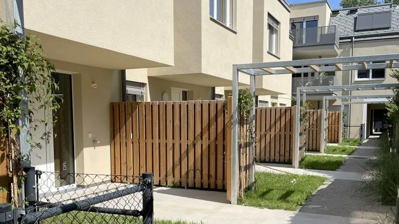 Reihenhäuser mit kleinen privaten Gärten und Holzzäunen in einer modernen Wohnanlage.