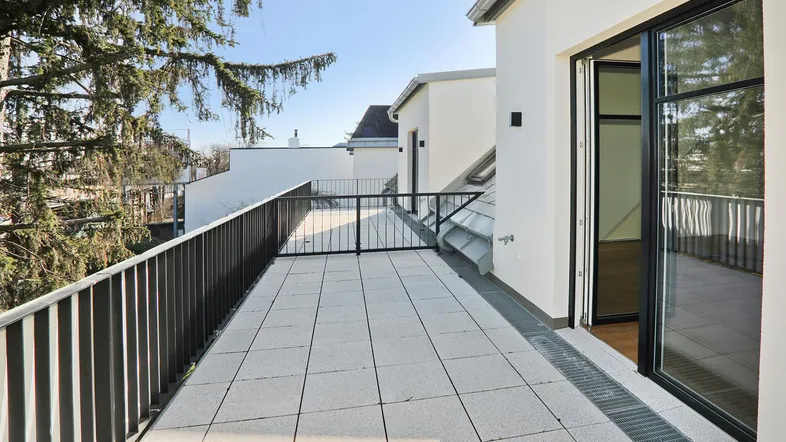 Geräumige Dachterrasse mit Fliesenboden und Blick auf die Umgebung, ideal für Entspannung im Freien.