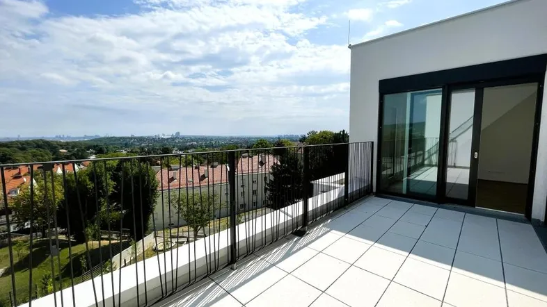 Große Dachterrasse mit hellen Fliesen, schwarzem Geländer und weitem Blick über die Stadt.