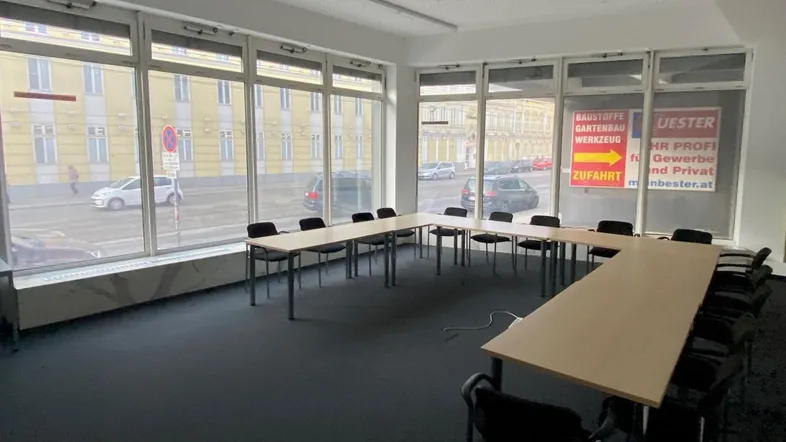 Großer Konferenzraum mit U-förmiger Tischordnung, Teppichboden und großen Fenstern zur Straße.