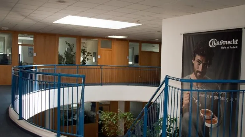 Geräumiger Bürogang mit blauen Geländern und Blick auf die untere Etage, umgeben von Büroräumen.